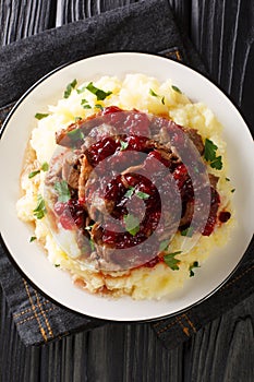 Delicious Reindeer meat served with potatoes and lingonberry sauce close-up in a plate. vertical top view photo