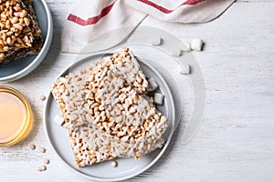 Delicious rice crispy treats on white wooden table, flat lay