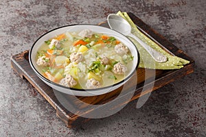 Delicious Rice soup with meatballs, celery, carrots, onions, potatoes and herbs close-up in a bowl. Horizontal