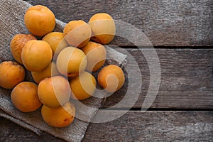 Delicious ripe apricots with napkin on wooden table, top view. Space for text