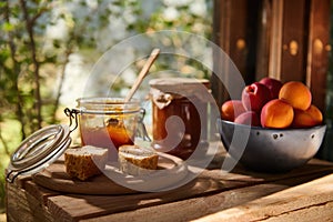 Delicious ripe apricots on wooden table with a jar of apricot jam and slices of homemade bread. Rustic style. Still life