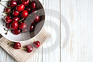 Delicious ripe cherry on white wooden background top view