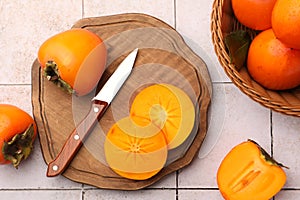 Delicious ripe juicy persimmons and knife on tiled surface, flat lay