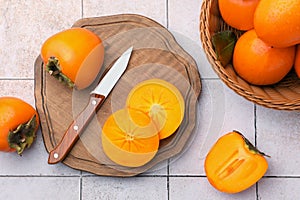 Delicious ripe juicy persimmons and knife on tiled surface, flat lay