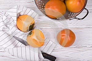 Delicious ripe persimmon fruit on white wooden background