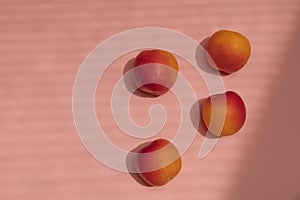 Delicious ripe sweet apricots on pink background with harsh shadows
