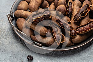 Delicious ripe tamarinds on a metal tray on a gray background, banner, menu, recipe place for text, top view