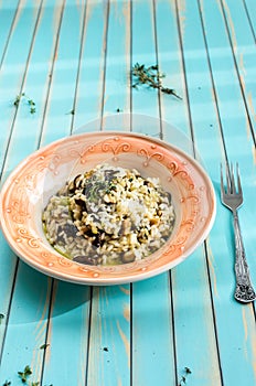 Delicious risotto with porcini mushrooms over wooden turquoise background