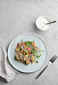 Delicious roasted Brussels sprouts with bacon served on grey table, flat lay