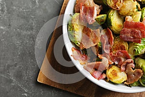 Delicious roasted Brussels sprouts with bacon served on grey table, top view