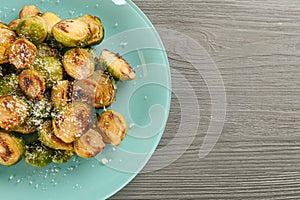 Delicious roasted brussels sprouts with grated cheese on wooden table, top view. Space for text