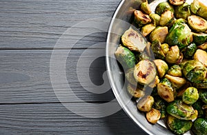 Delicious roasted brussels sprouts on grey wooden table. Space for text