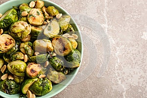 Delicious roasted brussels sprouts with peanuts on grey marble table, top view. Space for text