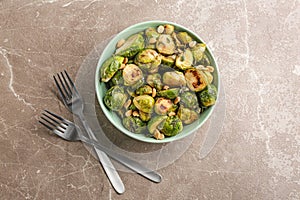 Delicious roasted brussels sprouts with peanuts on marble table, flat lay