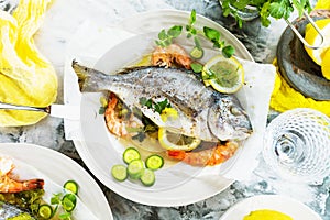 Delicious roasted dorado or sea bream fish with lemon and fresh Prawns