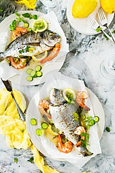 Delicious roasted dorado or sea bream fish with lemon and fresh Prawns