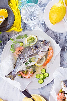Delicious roasted dorado or sea bream fish with lemon and fresh Prawns