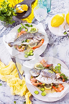 Delicious roasted dorado or sea bream fish with lemon and fresh Prawns