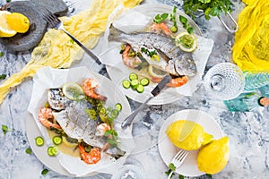 Delicious roasted dorado or sea bream fish with lemon and fresh Prawns