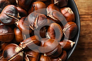 Delicious roasted edible chestnuts in bowl on table, top view