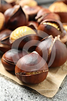 Delicious roasted edible chestnuts on grey table, closeup