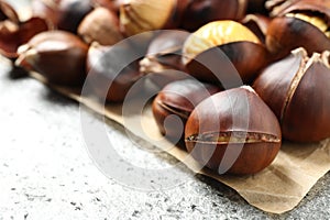 Delicious roasted edible chestnuts on grey table, closeup