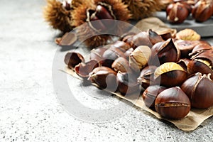 Delicious roasted edible chestnuts on grey table, closeup