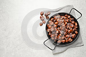 Delicious roasted edible chestnuts on light grey table, flat lay. Space for text