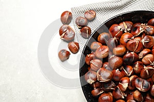 Delicious roasted edible chestnuts on light grey table, flat lay. Space for text