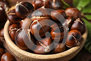 Delicious roasted edible chestnuts in wooden bowl, closeup