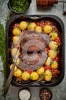 Delicious roasted goose breast served with vegetables, potatoes. Placed in metal baking dish