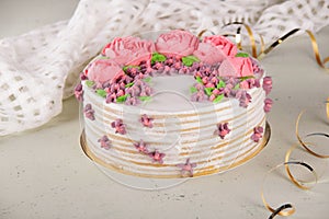 Delicious round cake decorated with cream flowers on table with napkin