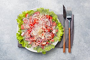 A delicious salad of crab sticks cherry tomatoes and grated cheese with onions in a serving plate