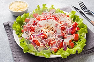 A delicious salad of crab sticks cherry tomatoes and grated cheese with onions in a serving plate