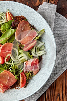 Delicious salad with prosciutto, mix of salads and tomatoes