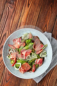 Delicious salad with prosciutto, mix of salads and tomatoes
