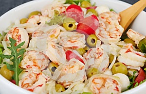 Delicious salad with shrimp, olives, mozzarella, tomatoes and olive oil sauce, close up