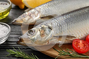 Delicious salted herrings and ingredients on black wooden table, closeup