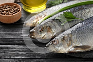 Delicious salted herrings and ingredients on black wooden table, closeup