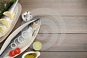 Delicious salted herrings and ingredients on wooden table, flat lay. Space for text