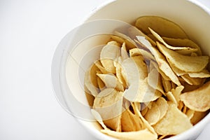 Delicious salted potato chips in a cardboard jar on a white background. Fast food