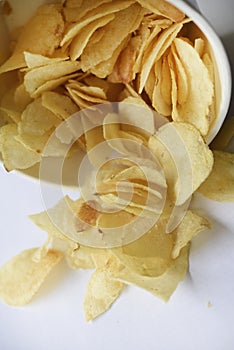 Delicious salted potato chips in a cardboard jar on a white background. Fast food