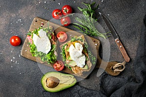 Delicious sandwich with avocado and poached egg on a dark background.