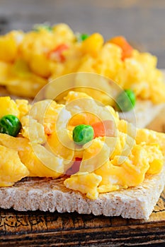 Delicious scrambled eggs with vegetables on crispy toast. Scrambled omelette toast recipe. Simple homemade cooking. Vertical photo
