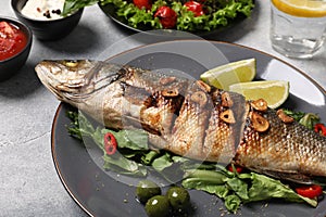 Delicious sea bass fish and ingredients on light grey table, closeup