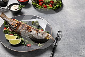 Delicious sea bass fish and ingredients served on light grey table