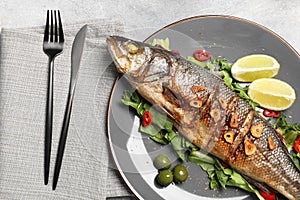 Delicious sea bass fish and ingredients served on light grey table, flat lay