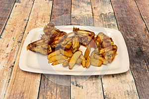 Delicious serving of fried chicken wings with barbecue sauce and French fries