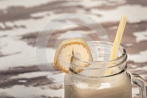 Delicious shake in cup with slice of banana