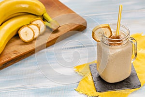 Delicious shake in cup with slices of fruit near bananas and cinnamon